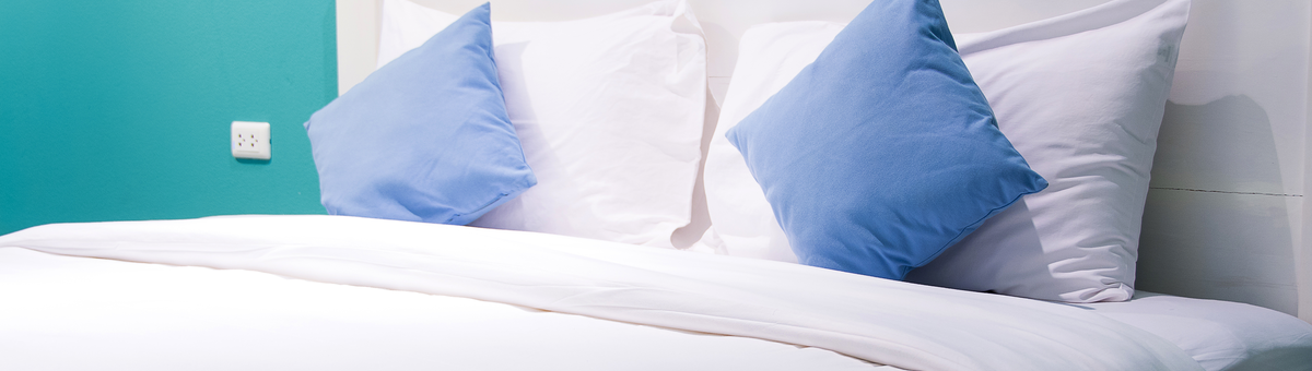 удобная большая continental кровать с белым постельным бельем и голубыми подушками