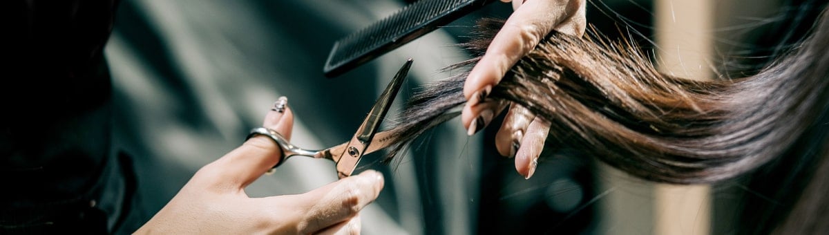 парикмахер стрижет женщине волосы ножницами