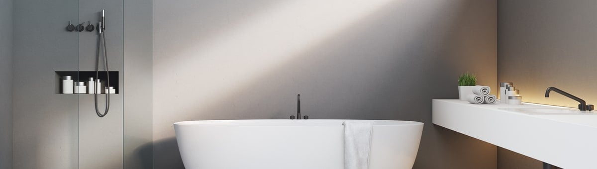 minimalistinio stiliaus vonios kambarys su vonia ir dusu prie pilkos sienos